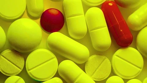 Assorted pills and capsules rotate on white background under yellow Stock-Footage 341970161