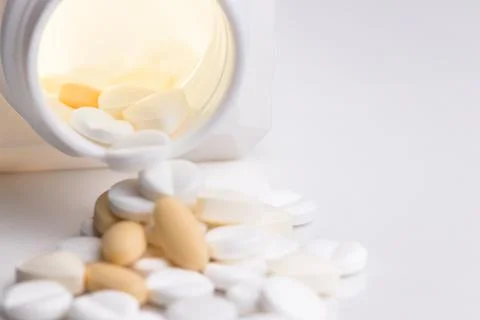 Assorted Pills Spilled From a Bottle on a White Background Stock Photos