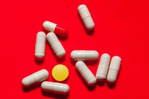 Assorted pills on vibrant red backdrop Stock Photos
