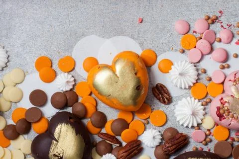 Assorted pink, orange, brown and green chocolate hearts with meringues, pecan Stock Photos