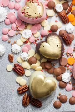 Assorted pink, orange, brown and green chocolate hearts with meringues, pecan Stock Photos