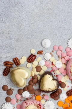 Assorted pink, orange, brown and green chocolate hearts with meringues, pecan Stock Photos