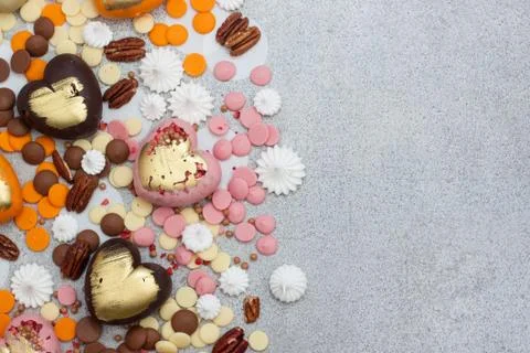 Assorted pink, orange, brown and green chocolate hearts with meringues, pecan Stock Photos