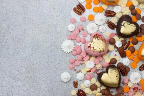 Assorted pink, orange, brown and green chocolate hearts with meringues, pecan Stock Photos
