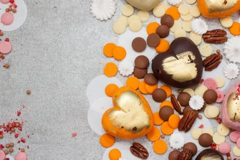 Assorted pink, orange, brown and green chocolate hearts with meringues, pecan Stock Photos