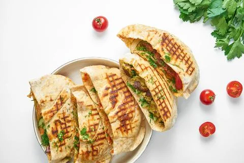 Assorted pita bread with vegetables, chicken and beef in a white plate on a l Stock Photos