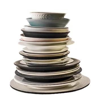 Assorted plates of different shapes, sizes and colours, all stacked one on top Stockfoto's