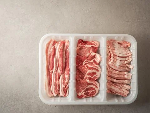 Assorted pork cuts on trays for packaging Stock Photos