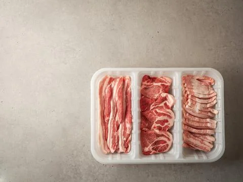 Assorted pork cuts on trays for packaging Stock Photos