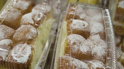 Assorted Powdered Sugar Donuts in Clear Plastic Tray On Bakery Display Shelf Video stock 328802909