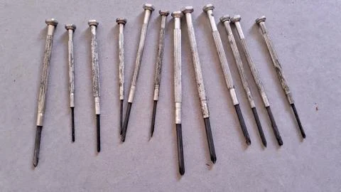 Assorted precision screwdrivers arranged in a row on grey background Stock Photos