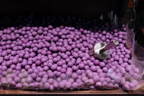 Assorted purple candy dragee balls with a scoop in a sweet shop display. Stock Photos