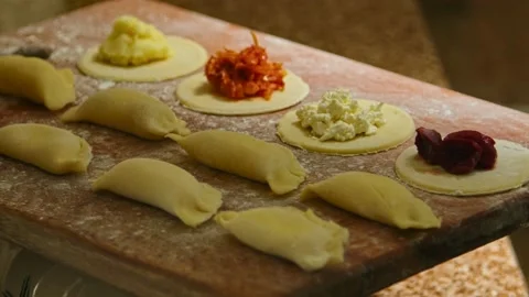 Assorted raw dumplings laid out on a board with flour, play with light Stock Footage 153805849