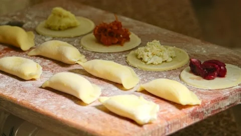 Assorted raw dumplings laid out on a board with flour, play with light Stock Footage 153805959