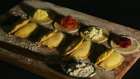 Assorted raw dumplings laid out on a board with flour, play with light Vídeos de archivo 153806054