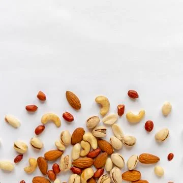 Assorted roasted and raw nuts scattered on white Stock Photos