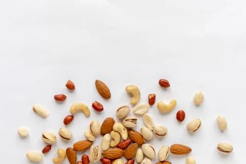 Assorted roasted and raw nuts scattered on white Stock Photos