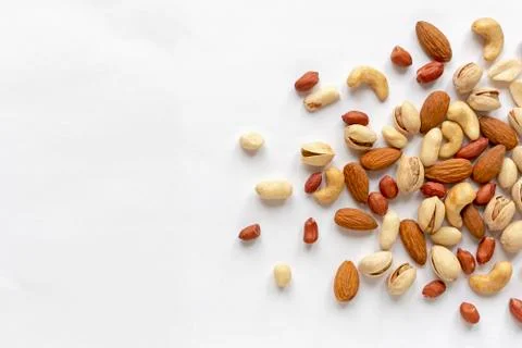 Assorted roasted and raw nuts scattered on white 스톡 사진