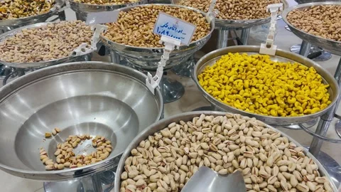 Assorted roasted nuts and snacks in metal bowls at store, horizontal Stock Footage 345156124