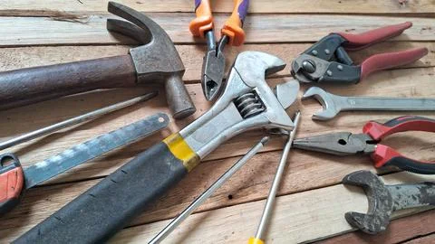 Assorted rusty metal hand tools arranged on a wooden background surface Stock Photos