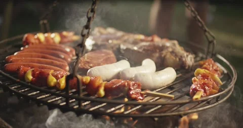 Assorted sausage skewer and steak sizzling on a round swing grill with rising Vídeo Stock 339977293