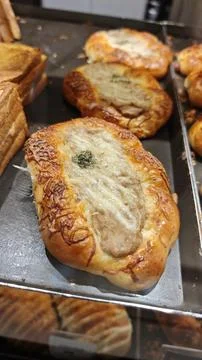 Assorted Savory Buns with Cheese and Herb Toppings on Bakery Display 写真素材