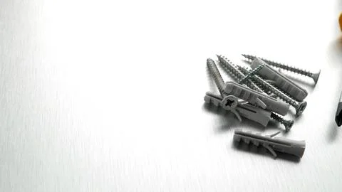 Assorted screws and plastic wall plugs on a brushed metal background Stock Photos