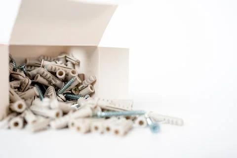 Assorted screws and wall plugs scattered from an open box on a white background Stock Photos