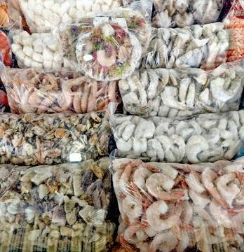 Assorted seafood packages displayed in clear plastic bags, including shrimp.. Stock Photos