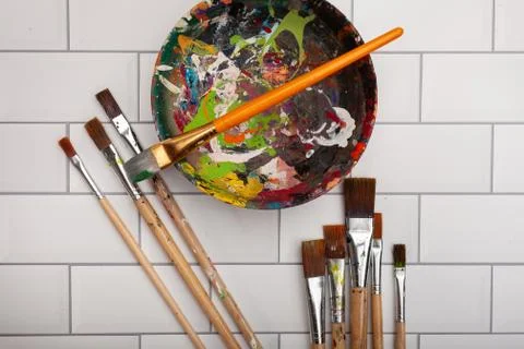 Assorted sizes of different paintbrushes laying on white subway tiles Stock Photos