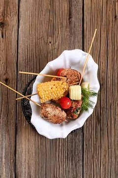 Assorted skewered appetizers on wooden table Stock Photos