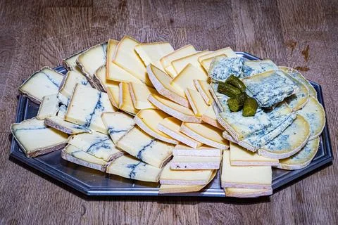 Assorted sliced cheeses including blue cheese arranged on a platter Stock Photos
