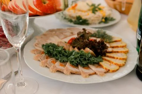 Assorted sliced meat appetizer with fresh greens on a festive table setting, Stock Photos