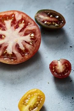Assorted sliced tomatoes on a light blue textured surface Stock Photos