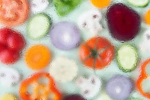 Assorted sliced vegetables on green background. Soft focus, water drops textu Stock Photos