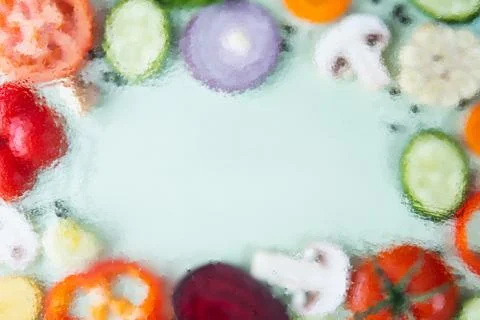 Assorted sliced vegetables on green background. Soft focus, water drops textu Stock Photos