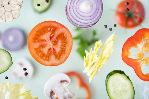 Assorted sliced vegetables levitating above green background Foto stock