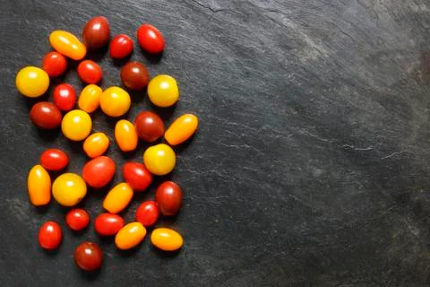 Assorted small tomatoes on slate with copy space Stock Photos