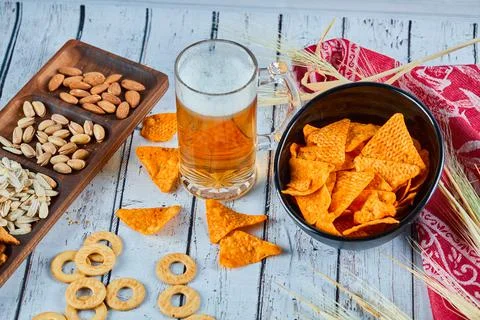 Assorted snacks, chips, and a glass of beer on blue table Stock Photos