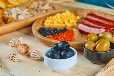 Assorted snacks, a plate of sausages, caviar, and olives on a wooden table Stock Photos