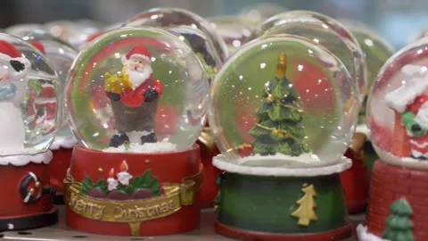 Assorted snow globes with trees and santas closeup of colorful shelf display Stock Footage 320236755