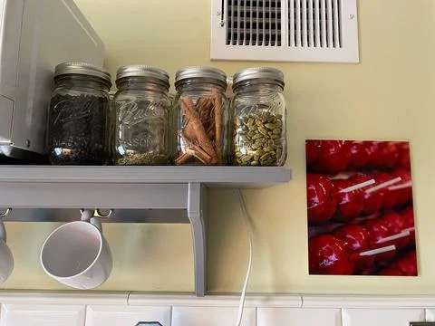 Assorted spices in glass jars on a shelf in a kitchen Stock Photos