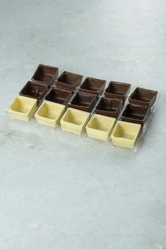 Assorted square-shaped chocolate shells inside molds vertical. Stock Photos