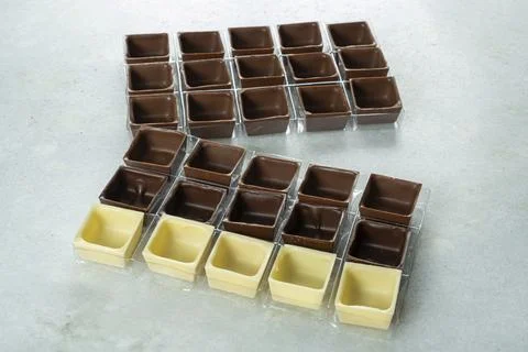 Assorted square-shaped chocolate shells inside molds fron view. Stock Photos