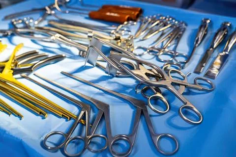 Assorted surgical tools and scissors on blue medical tray Stock Photos