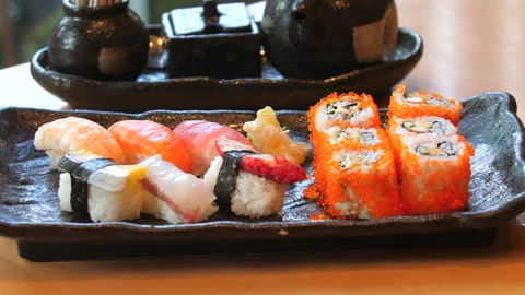 Assorted sushi platter with nigiri and rolls on black ceramic plate, Видео 292817533