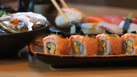 Assorted sushi platter with salmon rolls, nigiri, oysters on wooden Stock Footage 289127575