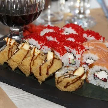 Assorted sushi rolls with red wine served on slate plate at elegant dinner .. Stock Photos