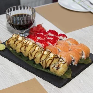 Assorted sushi rolls with soy sauce served on slate plate in restaurant setti Stock Photos