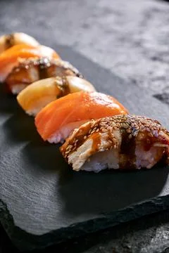 Assorted sushi with salmon, eel and escolar on black stone plate on dark Stock Photos